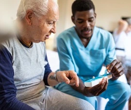 Home Care Specialist helping senior take his medicine. 